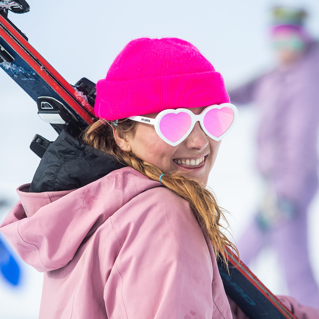 / Pink | Woman holding skis in The Miami Nights Admirer from Pit Viper Sunglasses