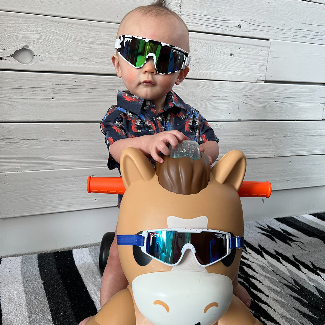 / Blue-Green | Baby on a toy horse in The Cowabunga Baby Vipes from Pit Viper Sunglasses