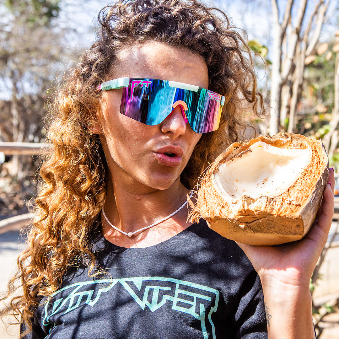 / Polarized Blue-Purple | Woman holding a coconut wearing Pit Viper Sunglasses