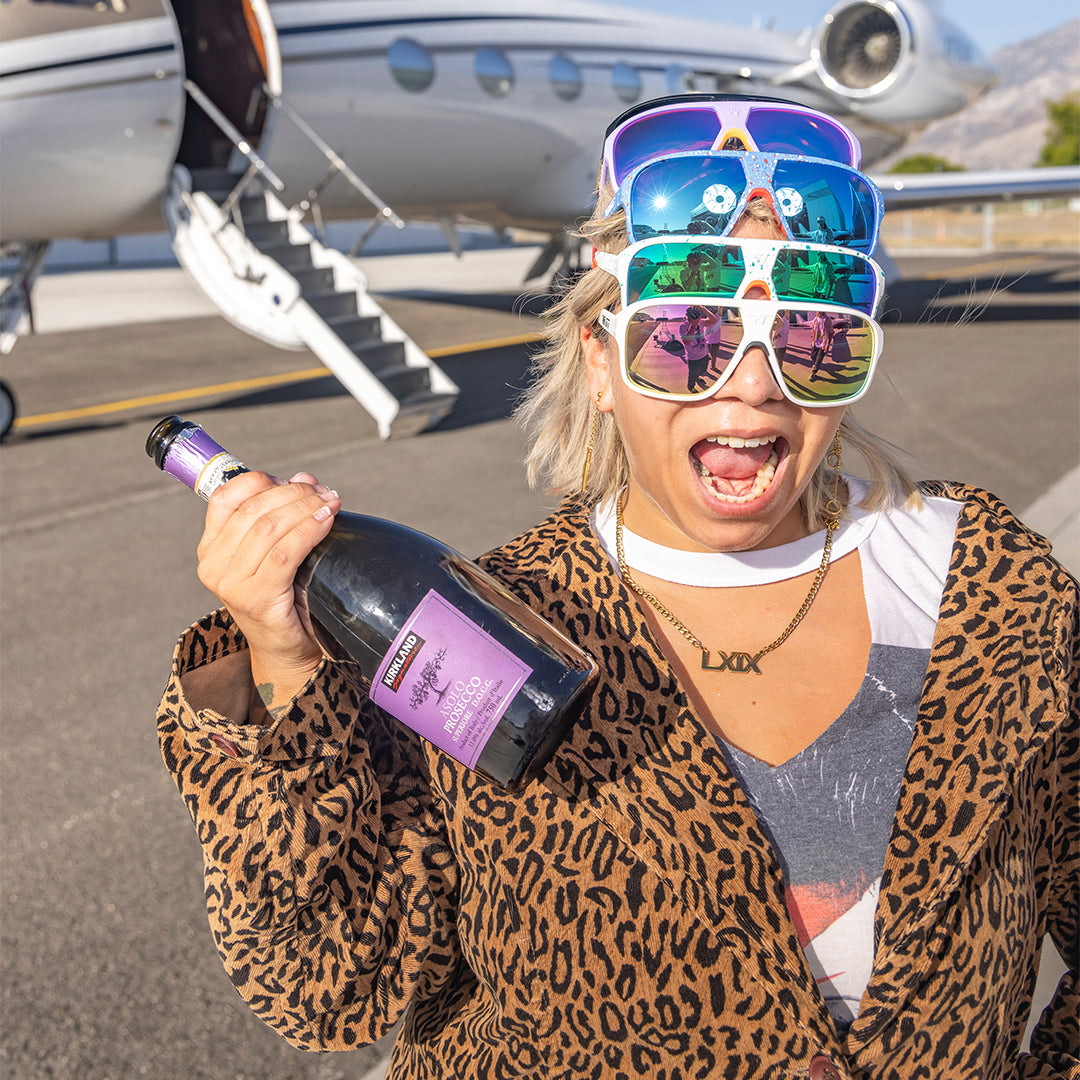 / Pink | Woman posing with champagne wearing multiple pears of Pit Viper Sunglasses