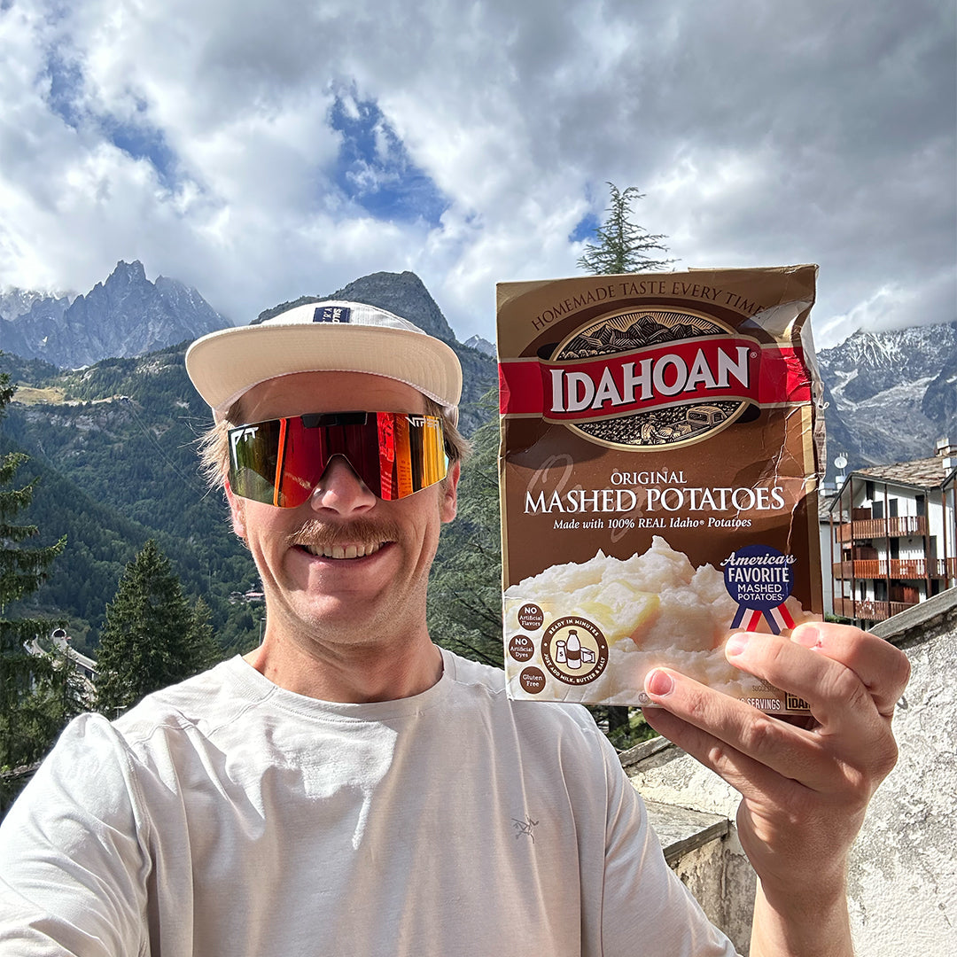 / Rainbow | A man smiling in the mountains with instant potatoes wearing Pit Viper Sunglasses